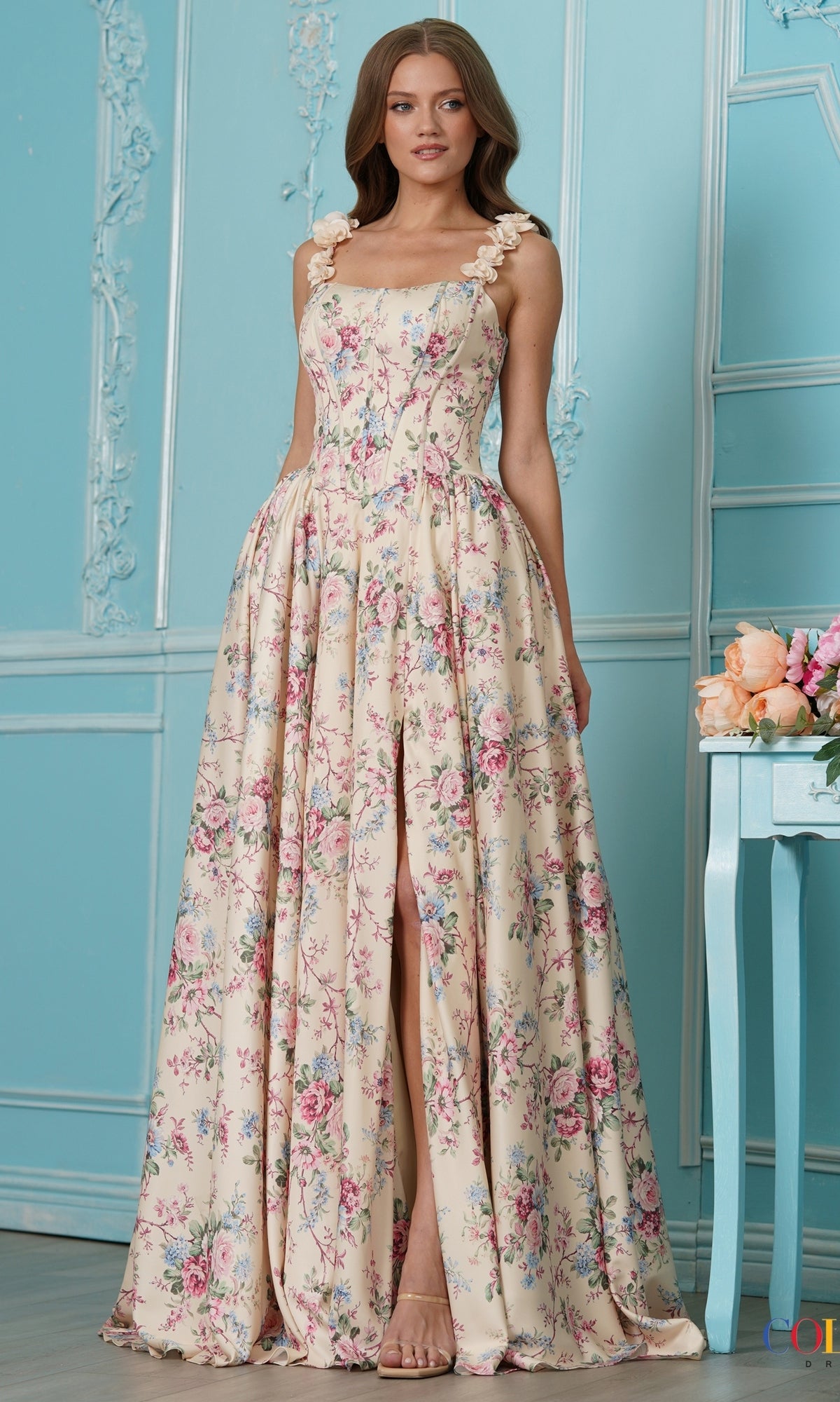 Long Prom Dress: Colors Dress 4214, a floor-length yellow floral A-line dress with rosette-detailed straps, a front leg slit, and a cottagecore aesthetic.